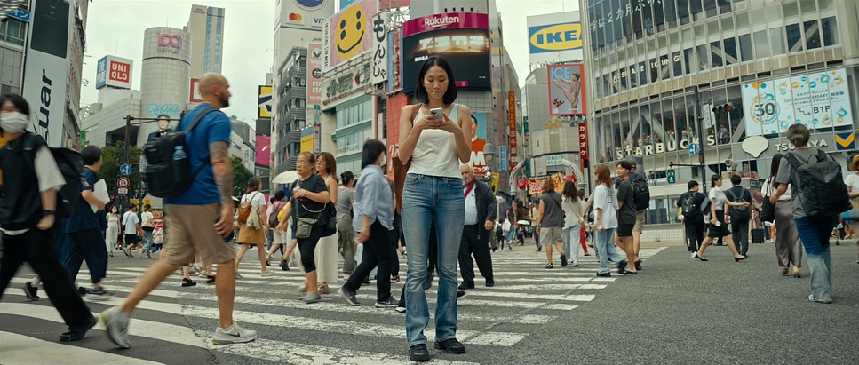 A woman crosses a busy city crosswalk while looking at her phone