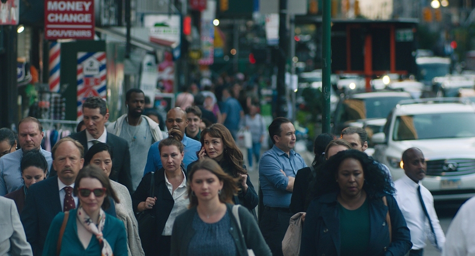 A dense crowd of pedestrians on a busy Manhattan sidewalk at dusk