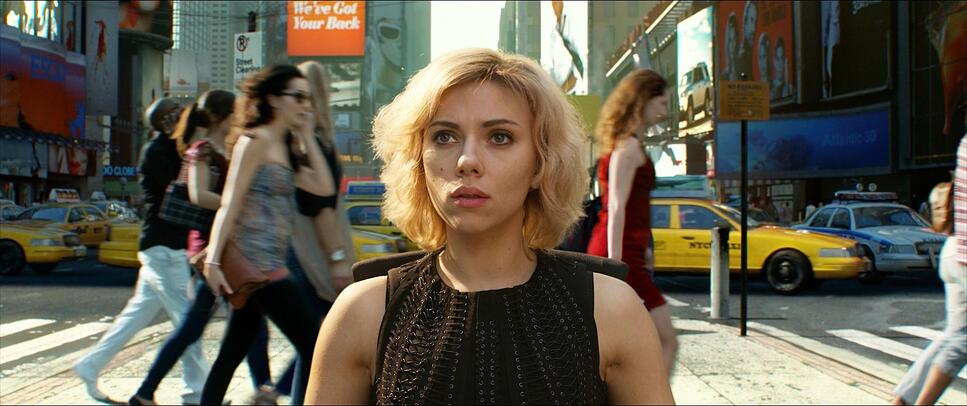 A woman stands still amid a blurred crowd in Times Square